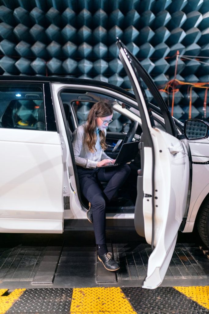 Sound engineer working on a laptop inside a car for acoustic testing in an anechoic chamber.